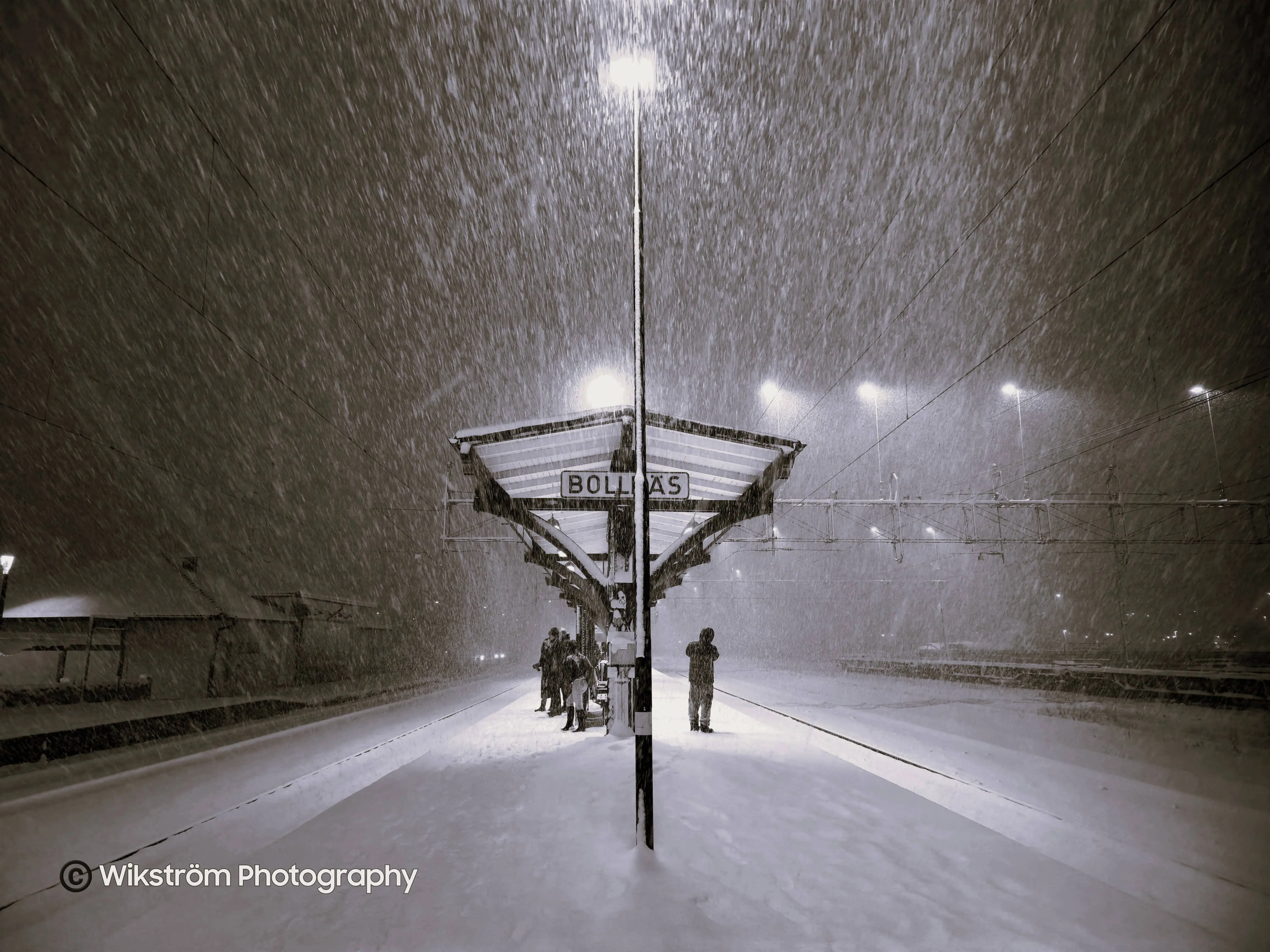 Heavy snowfall at a busy trainstation.